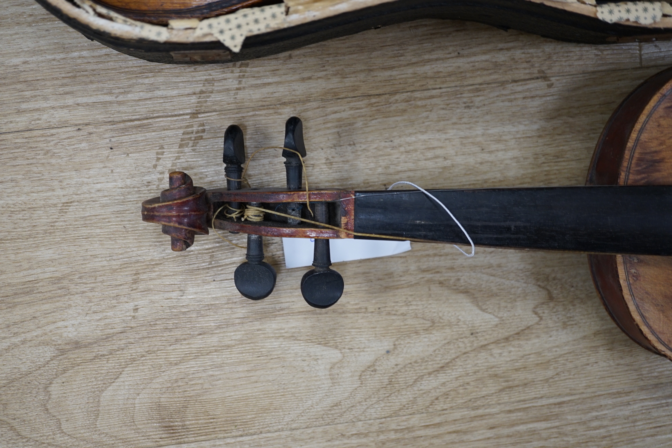 Two early 20th century violins, one in the remains of a case, both for restoration, length of bodies, 35.5cm and 36cm